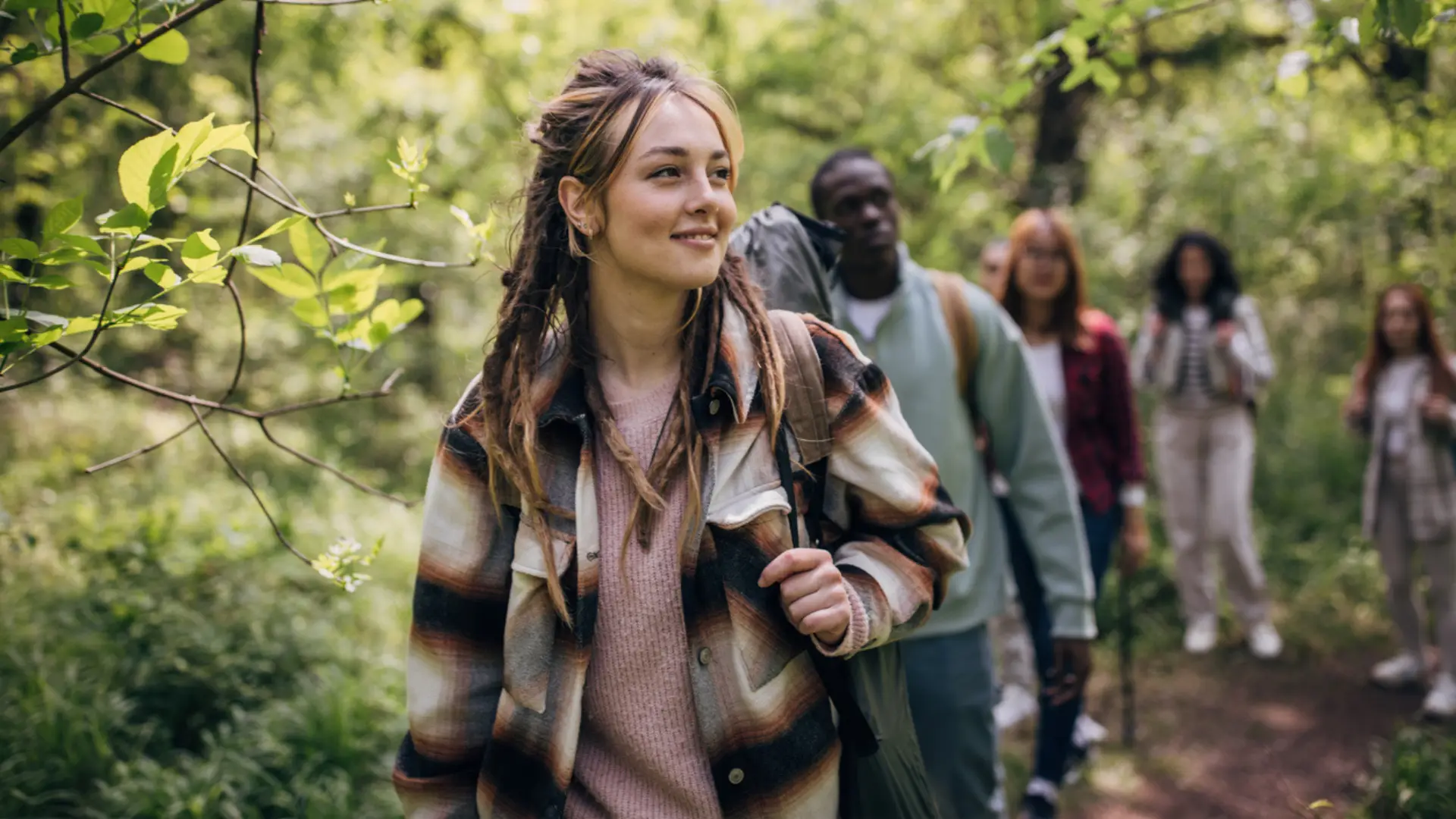 A group of friends led by a brunette woman with a backpack are hiking in the Triangle