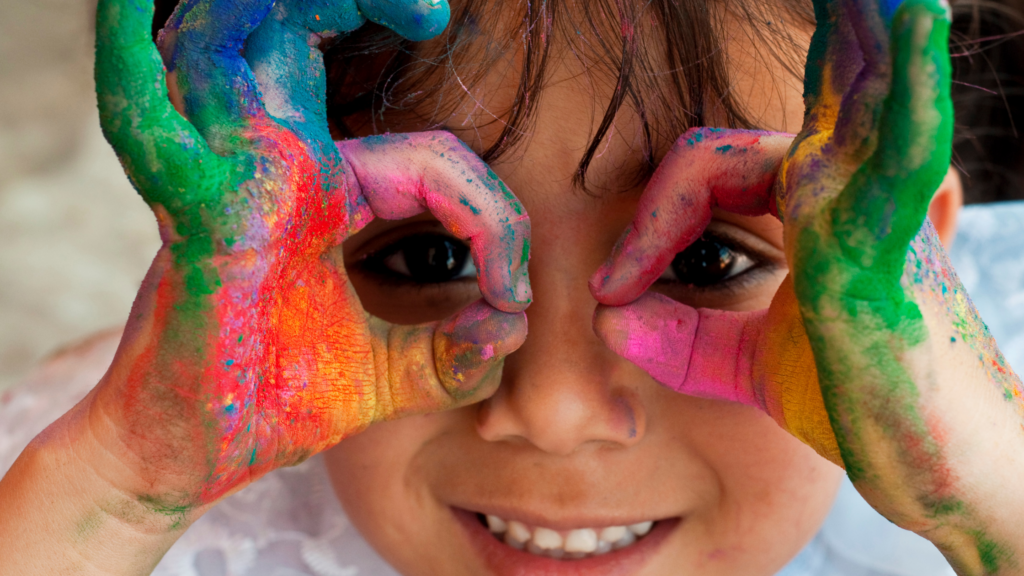 A child with paint on his hands holds his fingers up like glasses. This image goes with the story: Summer guide for parents in the Triangle