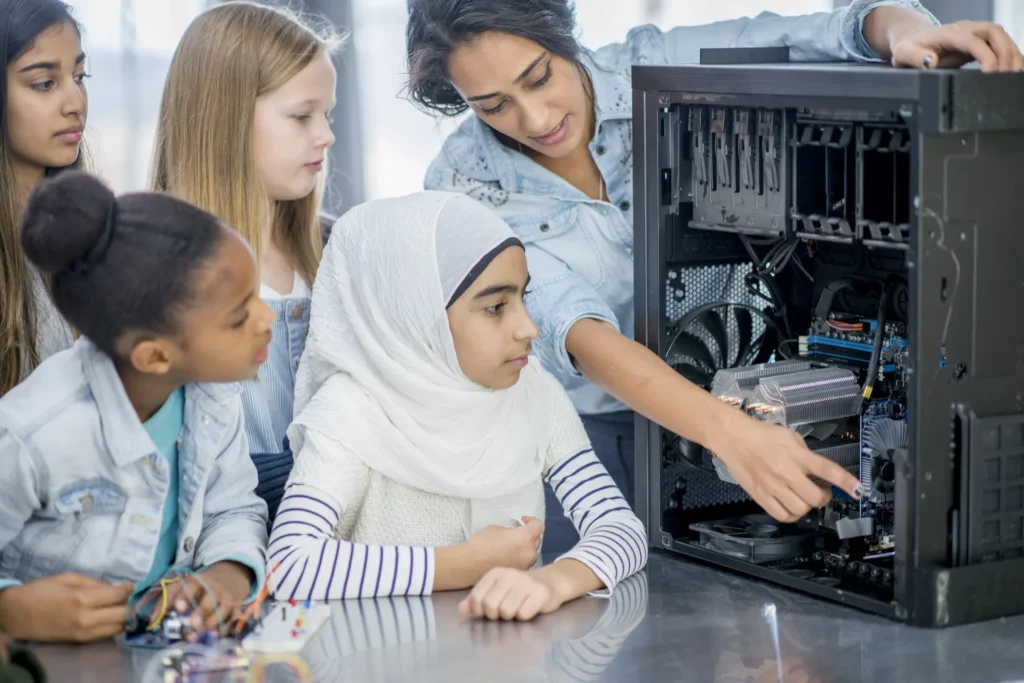 A woman points to parts inside of a computer to teach kids about engineering, which is part of STEM programs that are part of JAG's summer guide for parents in the Triangle