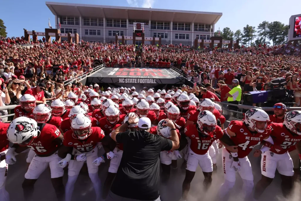 The NC State football team enters Carter-Finley Stadium on gameday. The Wolf Pack is a must-watch for football in North Carolina.