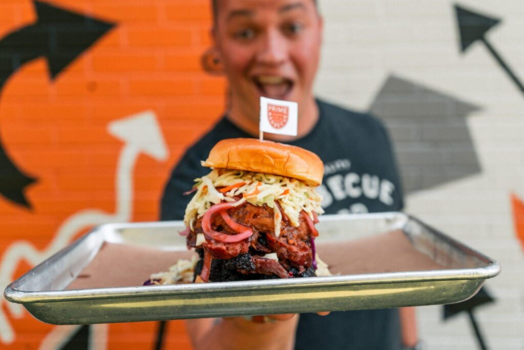 A man holds a barbecue sandwich from Prime Barbecue in Raleigh.