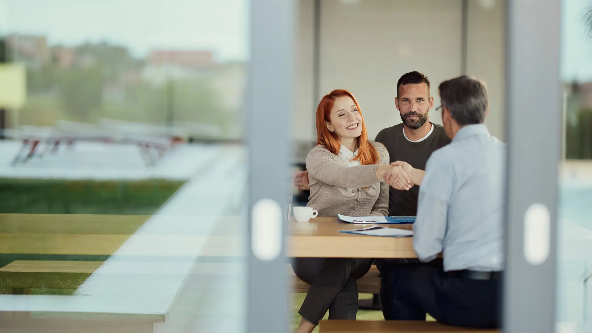 A woman and her husband shake hands with a local agent, illustrating the importance of local expertise when buying or selling a home in the Triangle