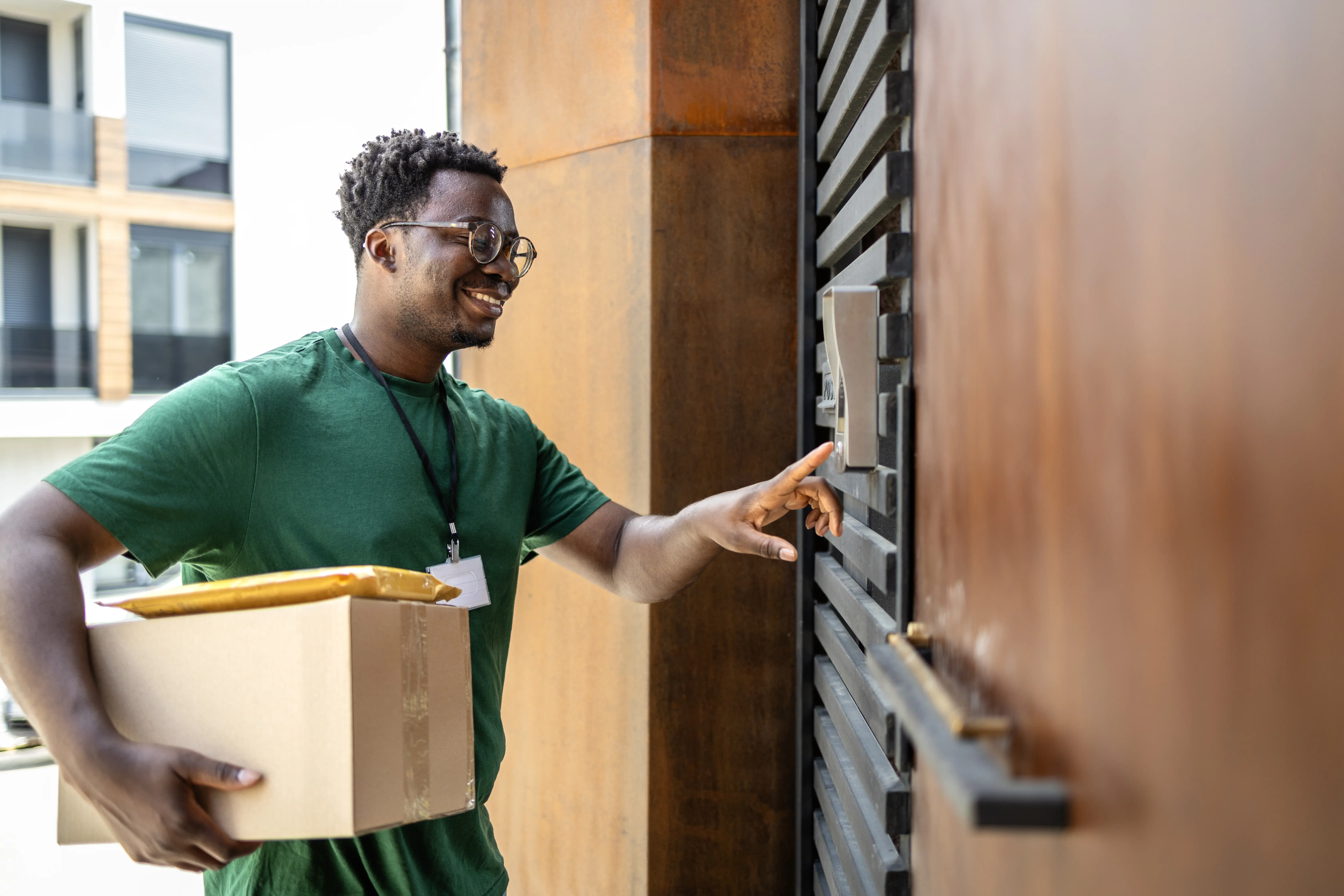 A delivery man enters a security code at a home's front door